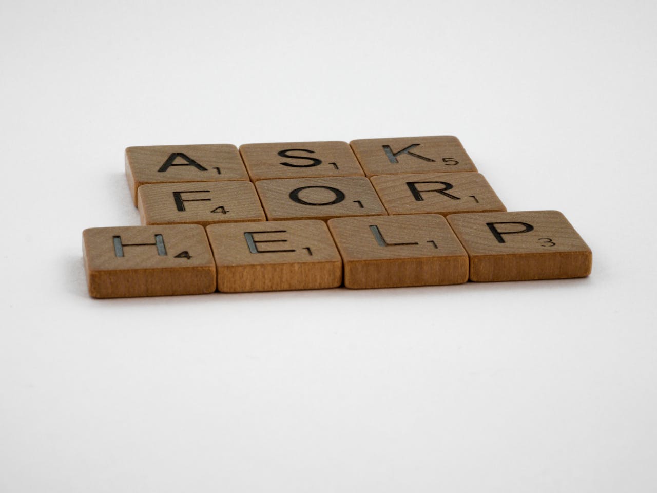 Services Scrabble tiles arranged on a white background forming the phrase 'Ask for Help', conveying a message of communication.